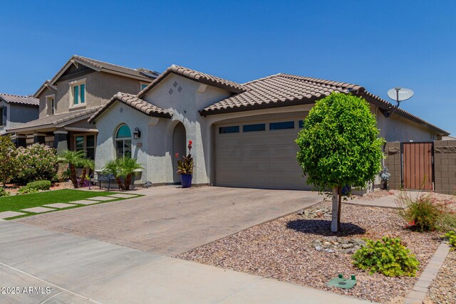 15276 W Latham St, Goodyear, AZ 85338 - mediterranean / spanish house featuring decorative driveway, an attached garage, stucco siding, a gate, and a tile roof