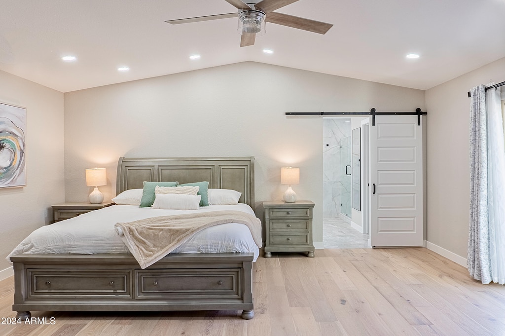 bedroom featuring ceiling fan, light hardwood / wood-style flooring, a barn door, and vaulted ceiling