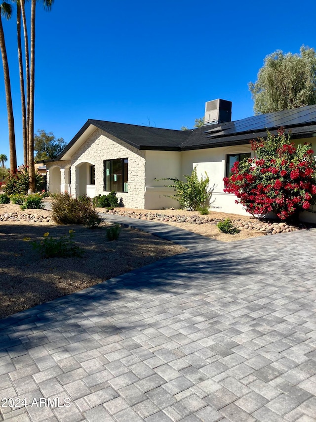 view of front of house with cooling unit and solar panels