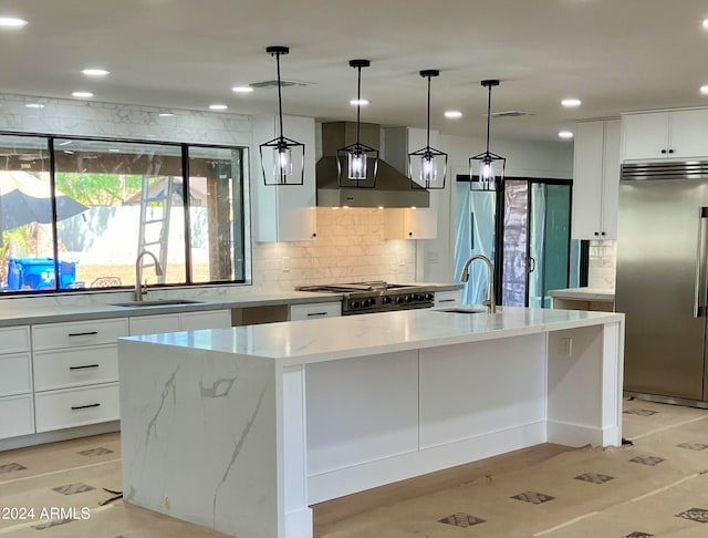 kitchen featuring decorative light fixtures, sink, a kitchen island with sink, premium appliances, and white cabinets