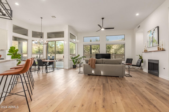 living room with ceiling fan with notable chandelier and light hardwood / wood-style floors