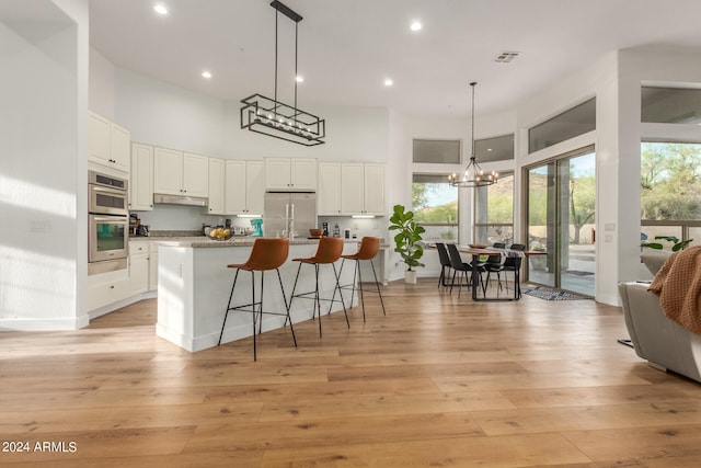 kitchen with a center island with sink, light hardwood / wood-style flooring, stainless steel appliances, and white cabinets