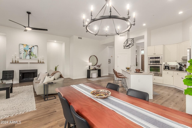 dining area featuring ceiling fan with notable chandelier and light hardwood / wood-style flooring