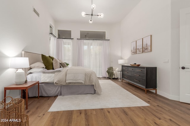 bedroom with wood-type flooring and a notable chandelier