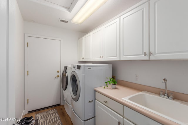 washroom featuring dark wood-type flooring, washer and dryer, cabinets, and sink