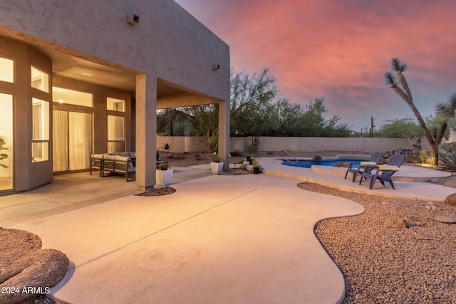 patio terrace at dusk with an outdoor hangout area and a fenced in pool