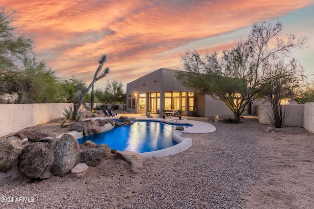 pool at dusk with a patio area