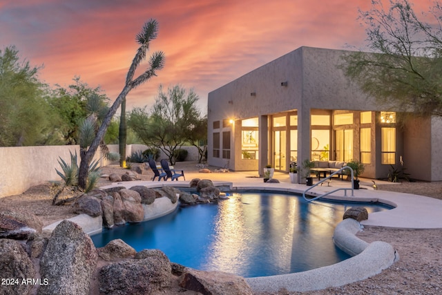 pool at dusk featuring a patio