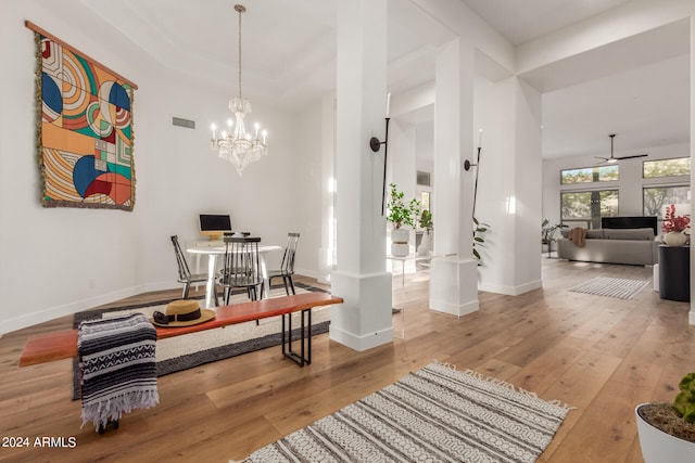 dining area featuring ceiling fan with notable chandelier, hardwood / wood-style floors, and decorative columns