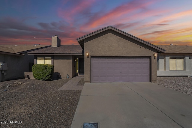 ranch-style house featuring a garage, stucco siding, driveway, and a chimney