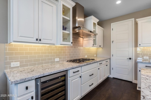 kitchen featuring beverage cooler, white cabinets, decorative backsplash, wall chimney exhaust hood, and stainless steel gas cooktop