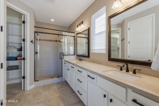 full bath with a spacious closet, a stall shower, and a sink