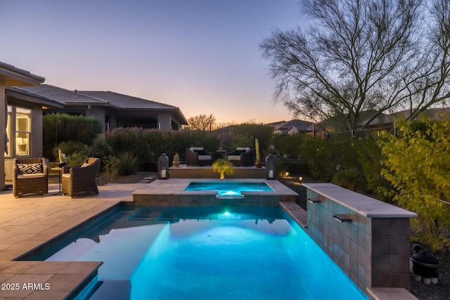 pool at dusk featuring a pool with connected hot tub and a patio area