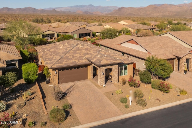 view of front of property with a garage, a residential view, a mountain view, and decorative driveway