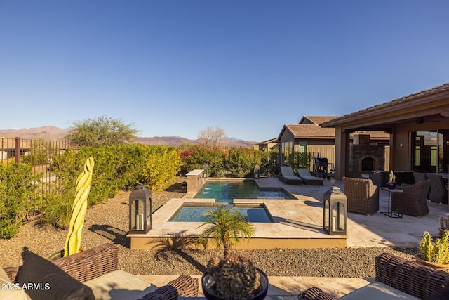 outdoor pool with a patio, a fenced backyard, a mountain view, an in ground hot tub, and an outdoor living space with a fireplace