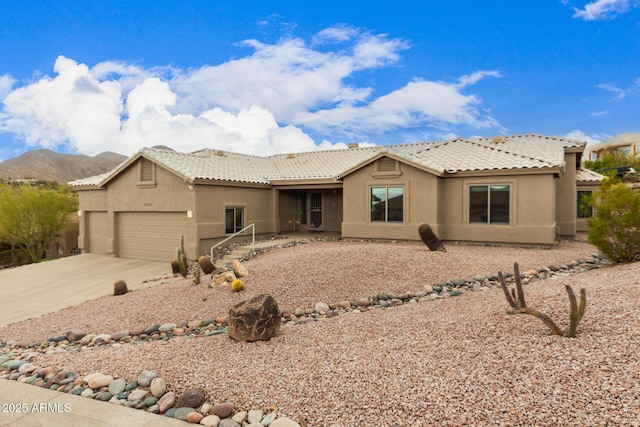 view of front of property with driveway, an attached garage, a tile roof, and stucco siding