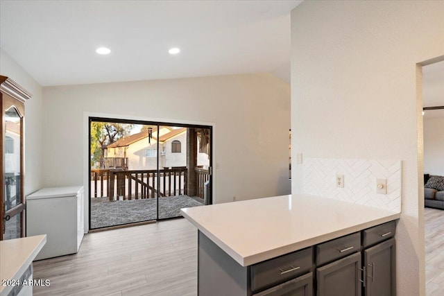 kitchen with kitchen peninsula, fridge, light hardwood / wood-style flooring, gray cabinets, and vaulted ceiling