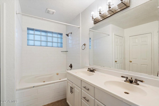 bathroom with vanity, a textured ceiling, and tiled shower / bath combo