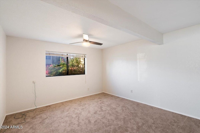 carpeted spare room with ceiling fan and beamed ceiling