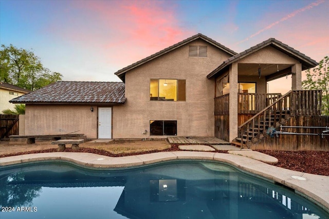 back house at dusk featuring a patio and a fenced in pool