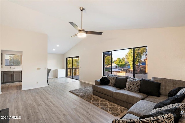 living room featuring ceiling fan, light hardwood / wood-style flooring, and high vaulted ceiling