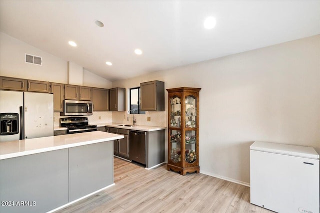 kitchen with stainless steel appliances, lofted ceiling, decorative backsplash, sink, and light hardwood / wood-style flooring