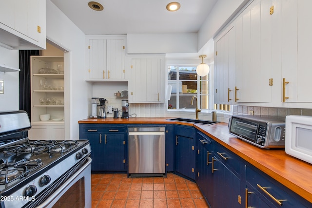 kitchen featuring a sink, blue cabinetry, stainless steel appliances, and wood counters