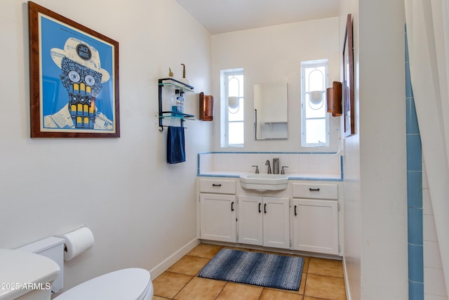 bathroom featuring vanity, baseboards, tile patterned floors, toilet, and backsplash