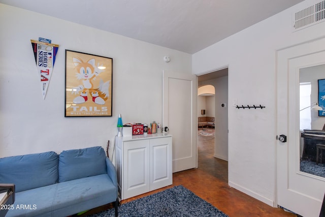 living area featuring arched walkways, visible vents, concrete flooring, and baseboards