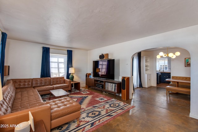 living room with plenty of natural light, finished concrete flooring, and arched walkways