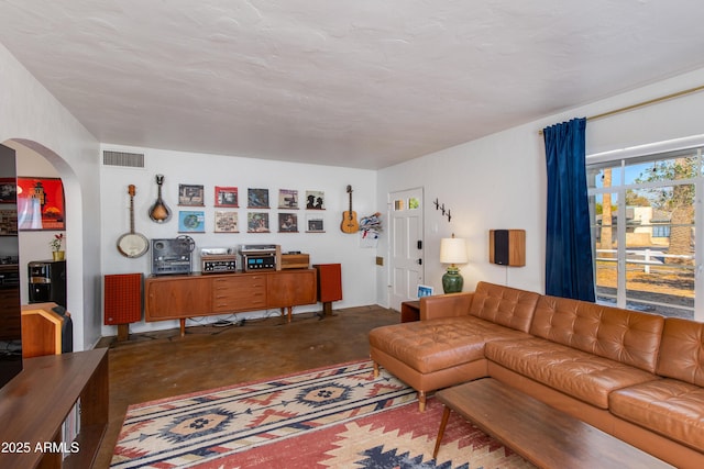 living room with visible vents, unfinished concrete flooring, and arched walkways