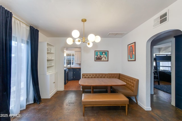 dining room featuring breakfast area, visible vents, arched walkways, and concrete floors