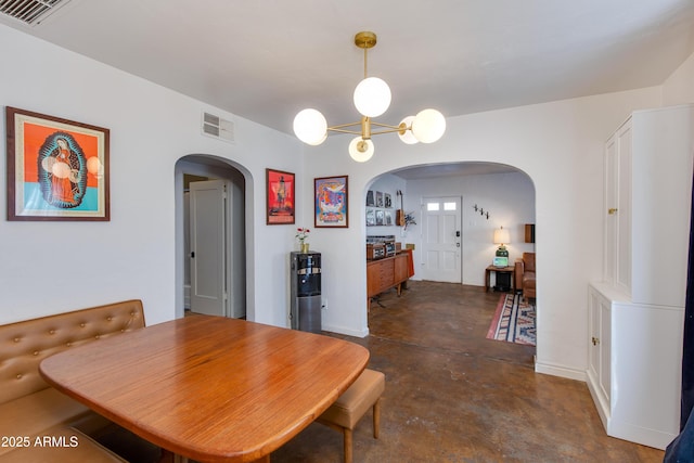 dining area featuring arched walkways, visible vents, concrete floors, and an inviting chandelier