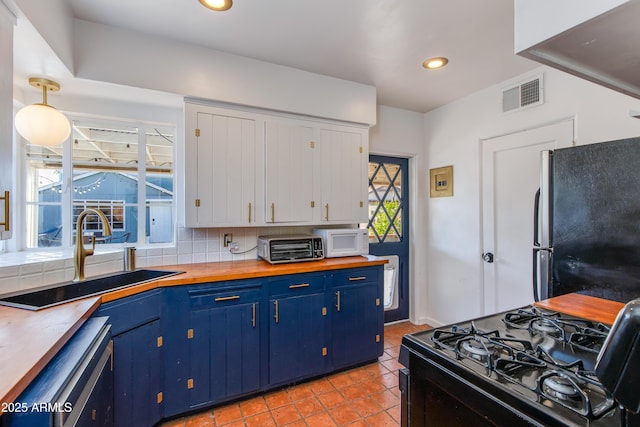 kitchen with visible vents, black appliances, a sink, blue cabinetry, and tasteful backsplash