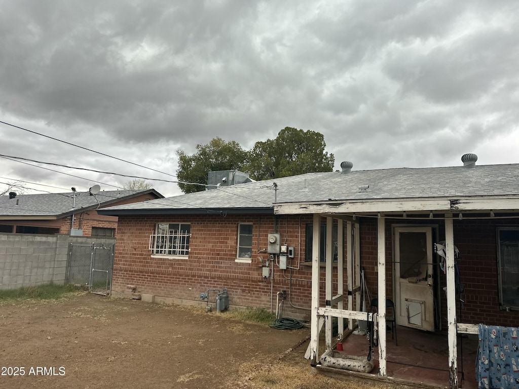 back of property with brick siding and fence