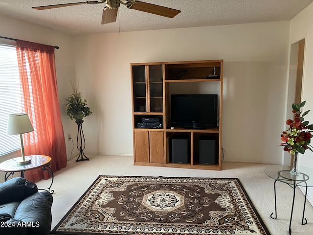 living room with light colored carpet, ceiling fan, and a textured ceiling