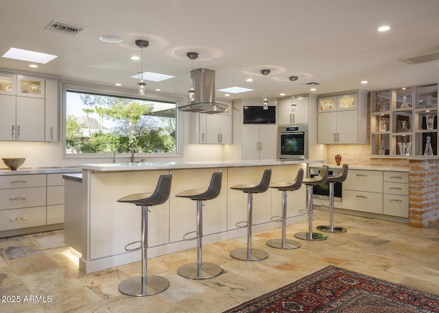 3921 E San Miguel Ave, Paradise Valley, AZ 85253 - kitchen with a skylight, a large island, stainless steel oven, island exhaust hood, and decorative light fixtures