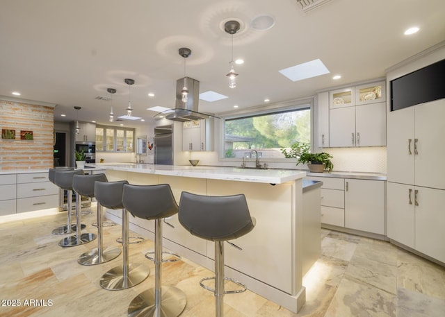 kitchen with white cabinetry, a skylight, a large island, and hanging light fixtures