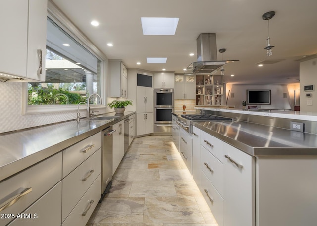 kitchen with island exhaust hood, a skylight, white cabinetry, and stainless steel appliances