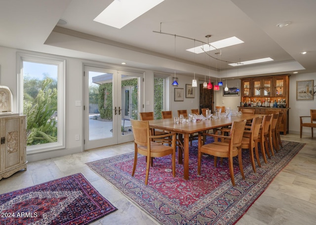 dining space featuring a raised ceiling, french doors, and a skylight