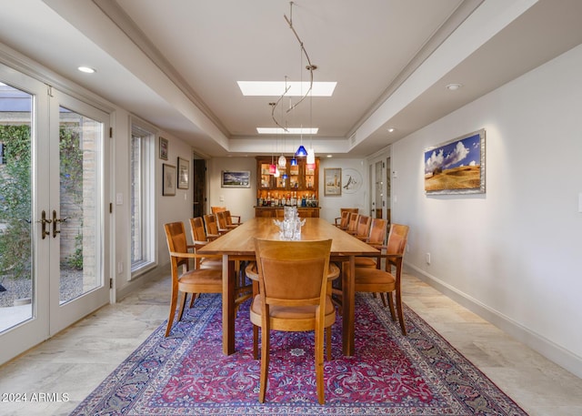 dining area with french doors, a skylight, a raised ceiling, and ornamental molding