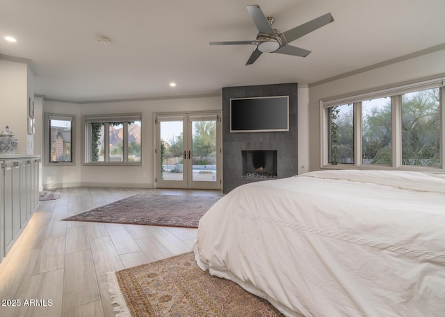 bedroom featuring access to outside, multiple windows, ceiling fan, and a tile fireplace