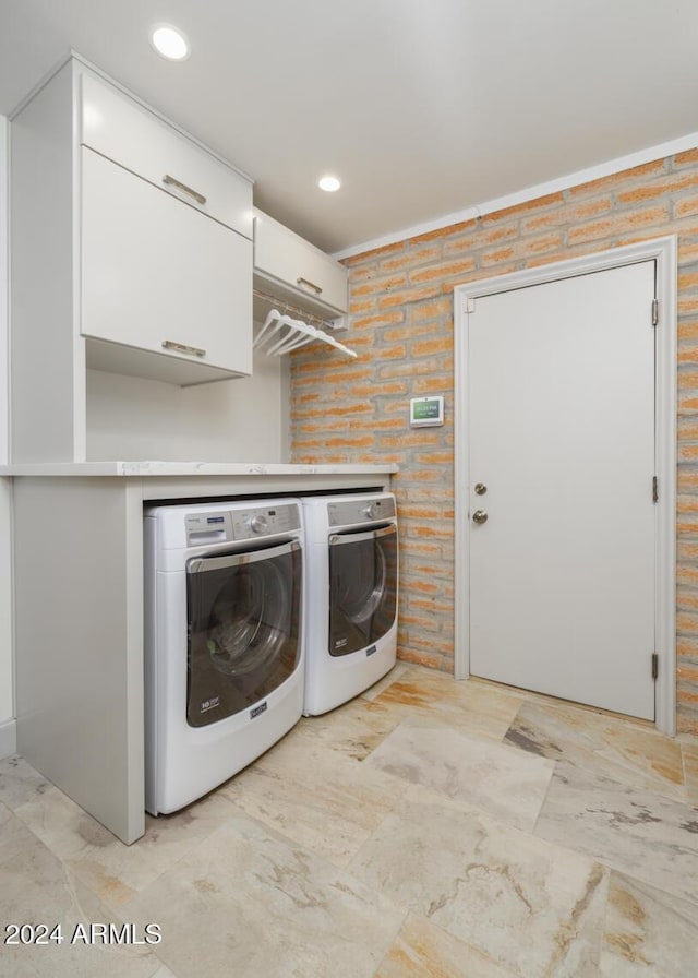 washroom with washer and clothes dryer and brick wall