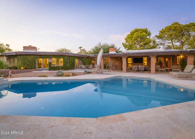 pool at dusk with a patio area