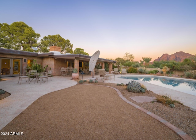 pool at dusk featuring a patio