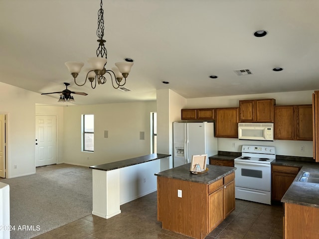 kitchen with dark carpet, ceiling fan with notable chandelier, white appliances, decorative light fixtures, and a center island