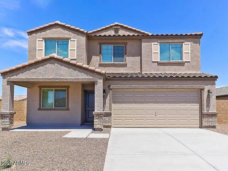 view of front of home with concrete driveway, a tiled roof, an attached garage, and stucco siding