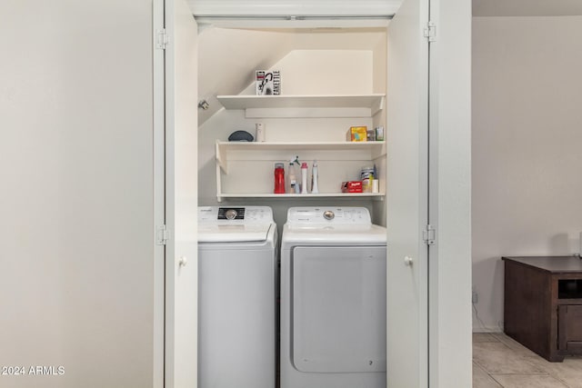 laundry area with independent washer and dryer and light tile patterned floors