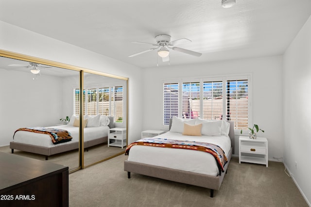 carpeted bedroom with a closet, multiple windows, baseboards, and ceiling fan