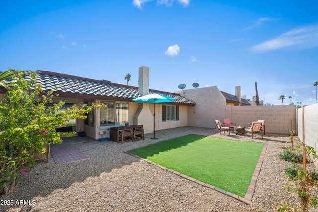 rear view of property featuring a fenced backyard, stucco siding, a tile roof, and a patio